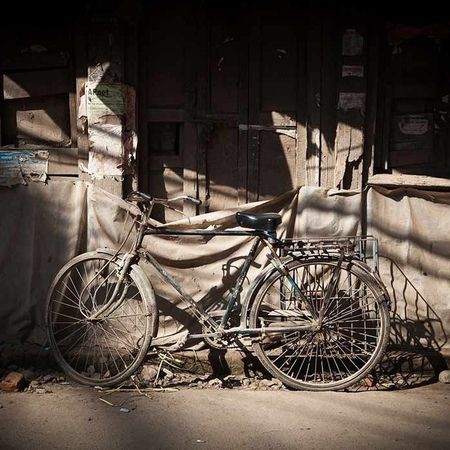 Ein altes, rostiges Fahrrad vor einem in Planen ummantelten Gebäude