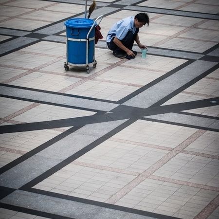 Ein Mann reinigt den Boden eines großen Platzes