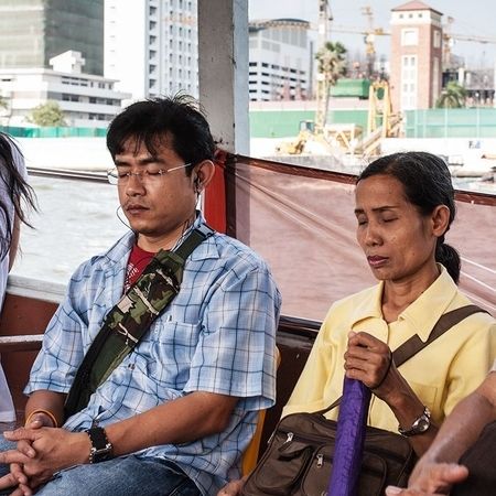 In einem Fahrzeug sitzen Personen nebeneinander, ein Mann hört Musik und hat ebenso wie die Frau neben sich die Augen geschlossen