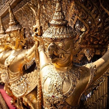 Goldene Statuen religiöser Figuren sind an einer Mauer nebeneinander angebracht