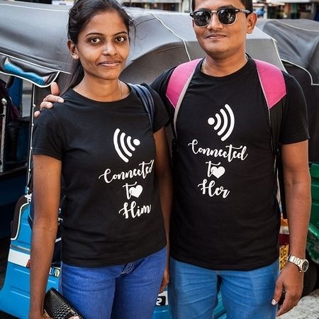 Zwei Personen in blauen Hosen und mit demselben schwarzen T-Shirt sehen in die Kamera