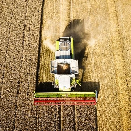 Drohnenaufnahme von einer Landwirtschaftsmaschine auf einem Weizenfeld