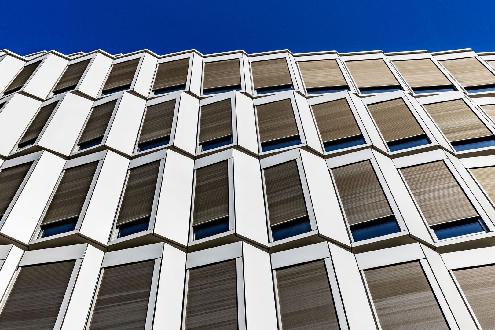 Geometrische Fassade eines modernen Gebäudes vor klarem blauen Himmel